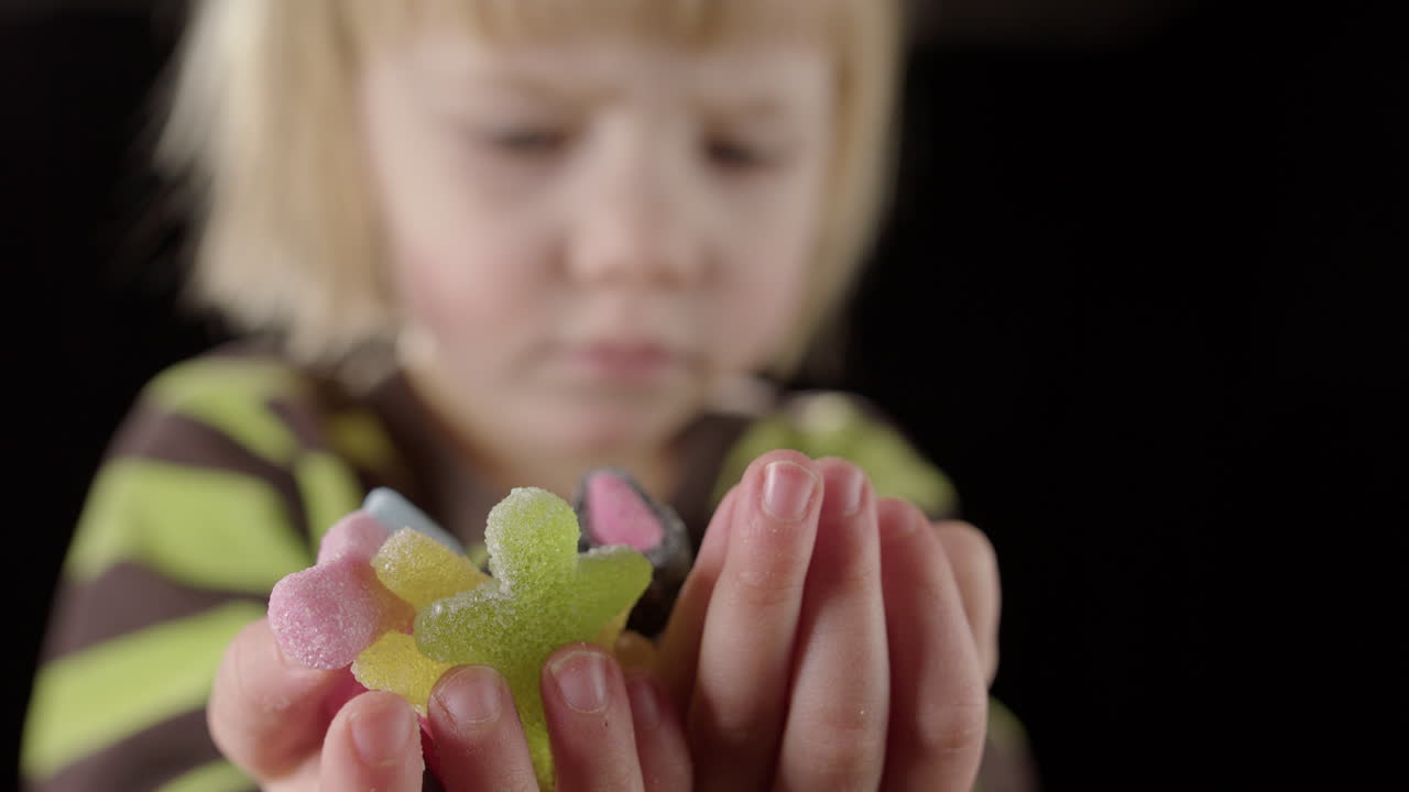 joven mira con deseo a los dulces caramelos de jalea en ambas manos, de cerca