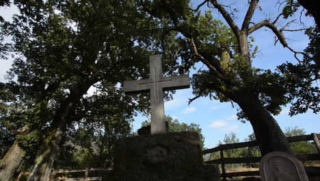 la cámara se desplaza desde un bosque de robles hasta una tumba cristiana