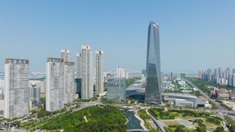 Panorámica-De-Arriba-A-Abajo-En-Incheon-Corea-Del-Sur,-Edificios-En-Primer-Plano-Y-Fondo-Con-Espacios-Verdes-Debajo