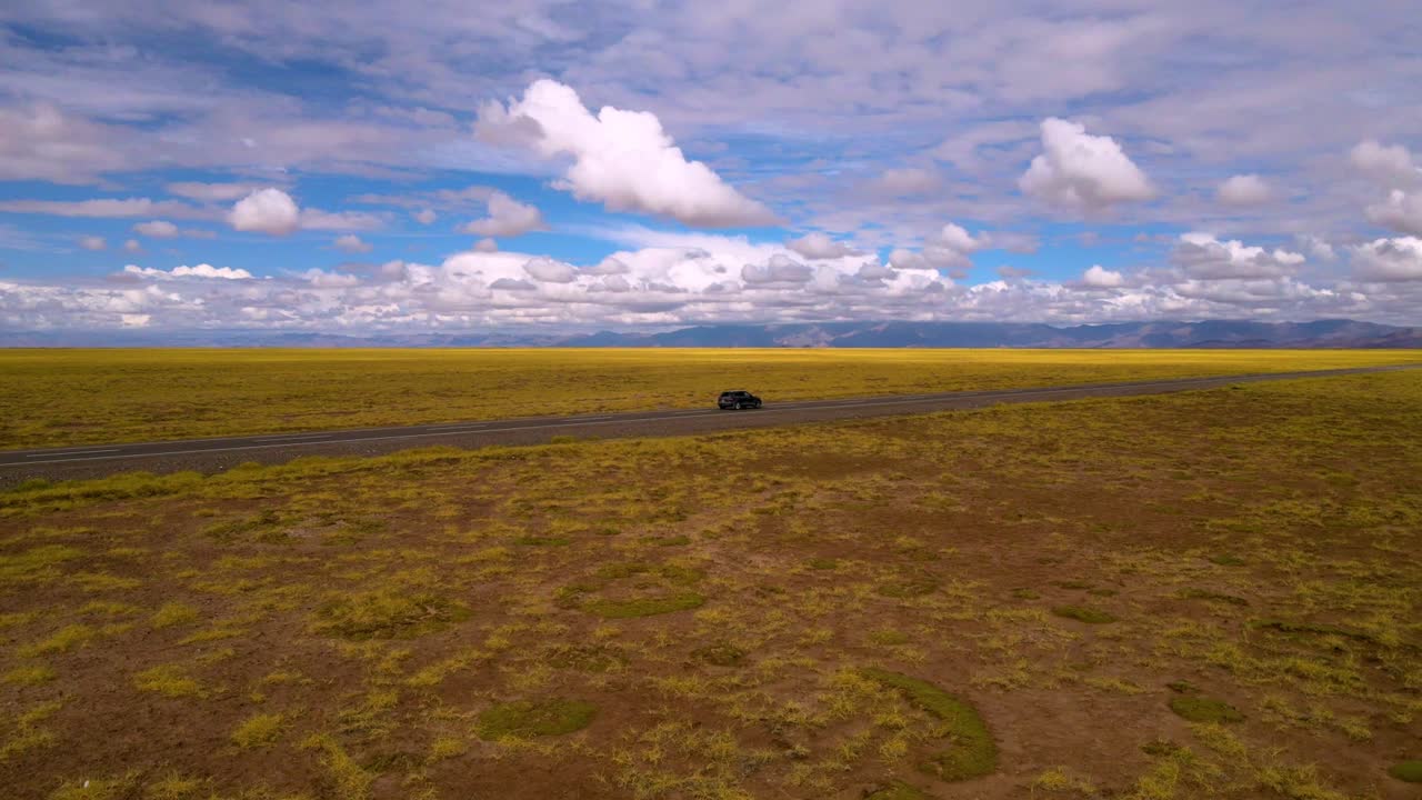 아르헨티나 살타와 주주이의 국경에 있는 살리나스 그란데스 소금 호수를 가로지르는 직선 도로를 달리는 회색 자동차 주위를 날아다니는 드론 촬영