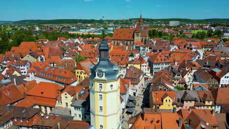 4k aerial drone video of the historic herrieder clock tower and the st. johannis church in the old town area of downtown ansbach, germany