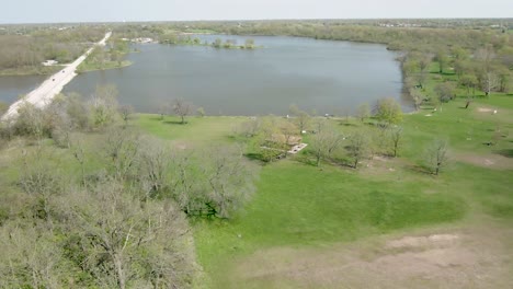 Aerial-circulating-around-a-pavilion-in-a-public-park-near-a-small-lake-in-rural-area