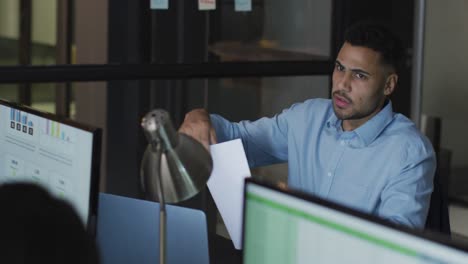 Video-of-biracial-businessman-passing-document-to-colleague-at-night-in-office