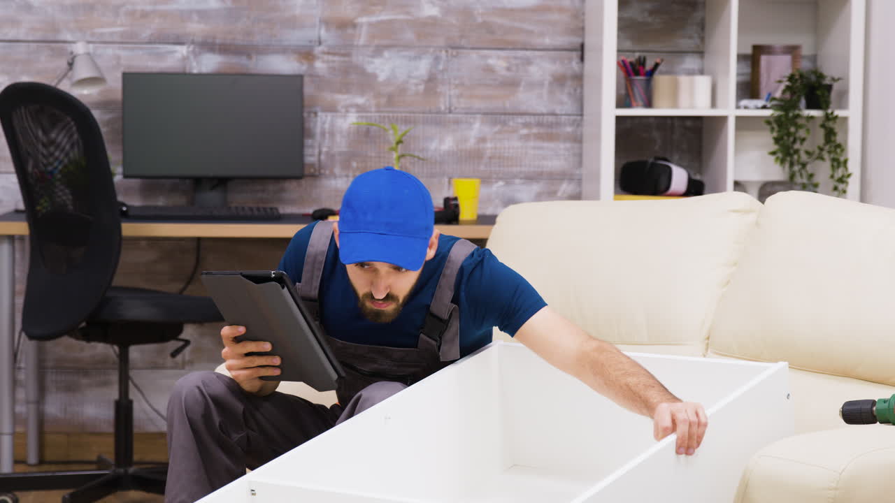 Man assembling furniture using a tablet in a home office