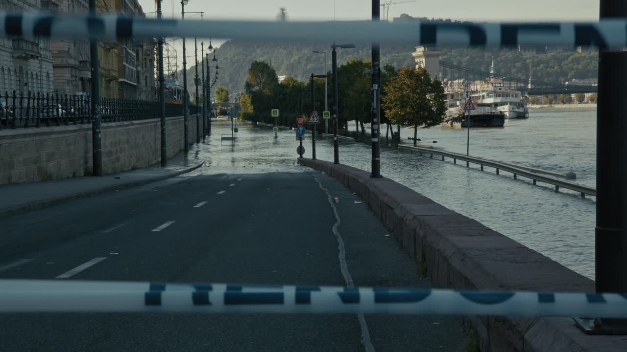 Flooded riverside road blocked by tape, leading to submerged area near the river, Budapest, Hungary
