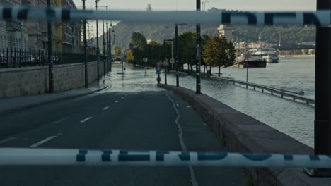 flooded riverside road blocked by tape, leading to submerged area near the river, budapest, hungary