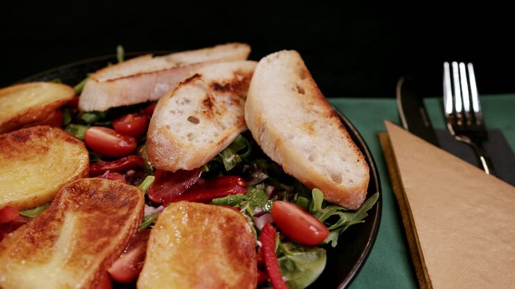 Deliziosa insalata fresca servita con pane all'aglio tostato su piatto nero