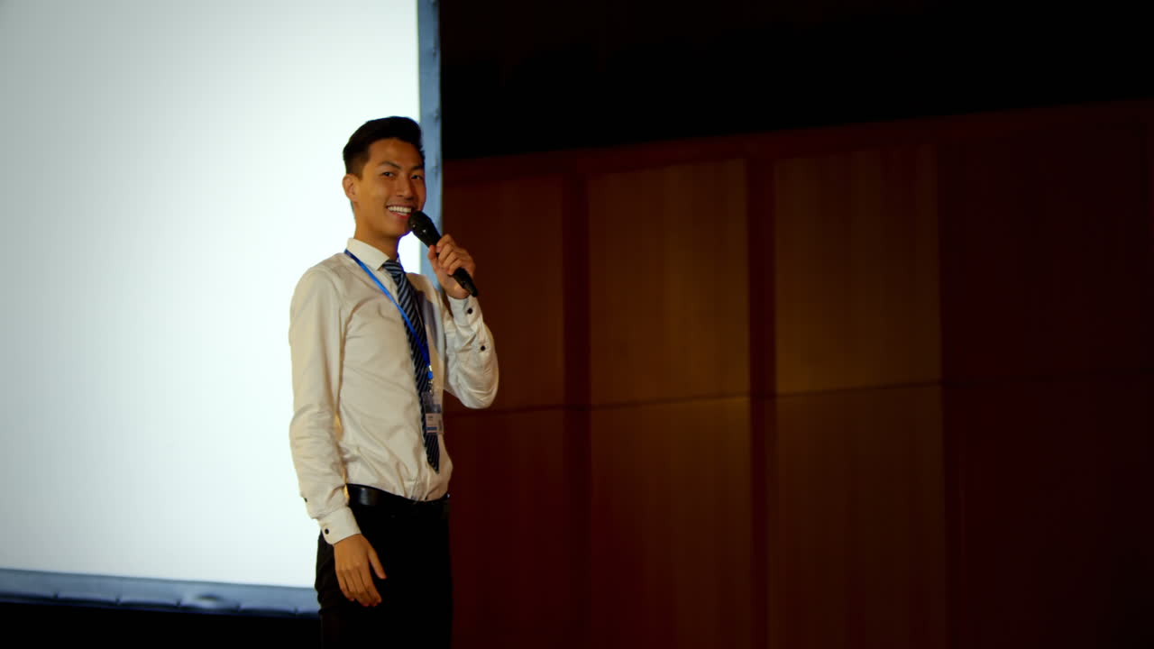Jovem empresário asiático falando em seminário de negócios em auditório 4k