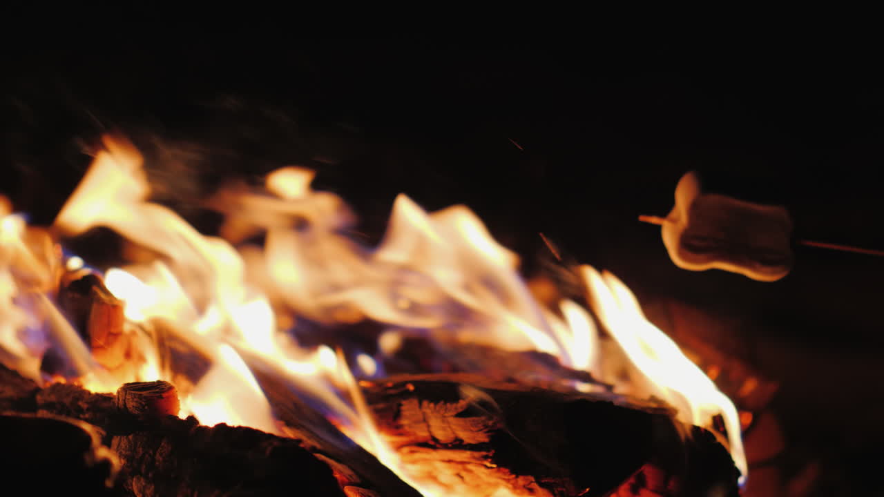 freír malvaviscos sobre un primer plano de fuego en el marco solo puedes ver palos con malvaviscos