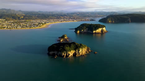 vista aérea de whenuakura y la isla de hauturu con una vista de la ciudad de whangamata en la isla norte, nueva zelanda