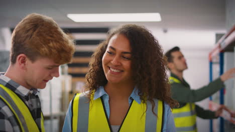 female team leader in warehouse training male intern standing by shelves