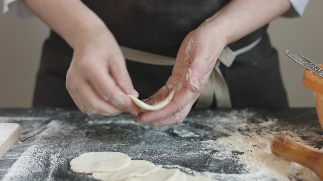 Two hands making meat dumplings.