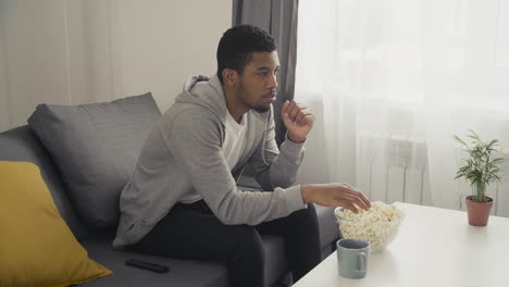 young man watching attentively a movie and eating popcorn 2