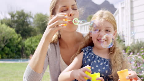 mother and daughter blowing bubbles in the yard happy family home