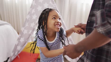 Happy-african-american-father-and-daughter-dancing-and-having-fun-at-home