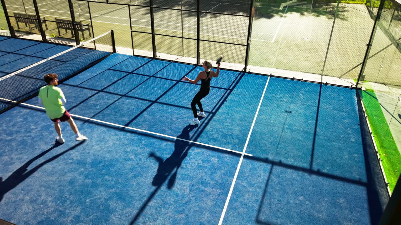 Luftaufnahme von zwei Personen, die Padel-Tennis auf einem blauen Platz spielen