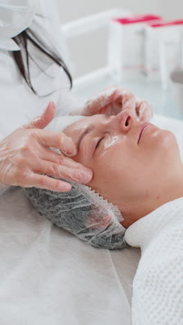 terapeuta de cosmetología haciendo mujer relajante spa masaje facial con las manos en el salón de desintoxicación y curación
