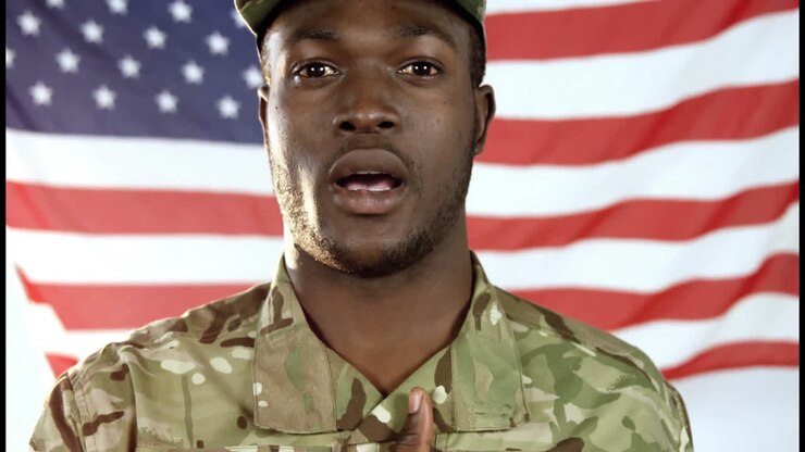 Personale militare in piedi davanti alla bandiera americana, che indossa un'uniforme mimetica
