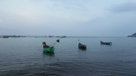 A-small-group-of-Vietnamese-fishing-boats-in-shallow,-calm-water-before-sunrise