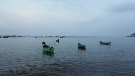 a small group of vietnamese fishing boats in shallow, calm water before sunrise