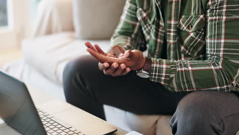 man experiencing hand pain while working on laptop