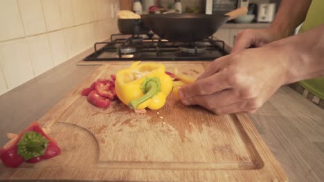 red and yellow capsicum chopped in wooden board in kitchen's countertop