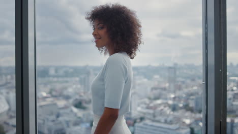 Businesswoman-standing-in-office-with-city-view.-Manager-turning-to-the-camera