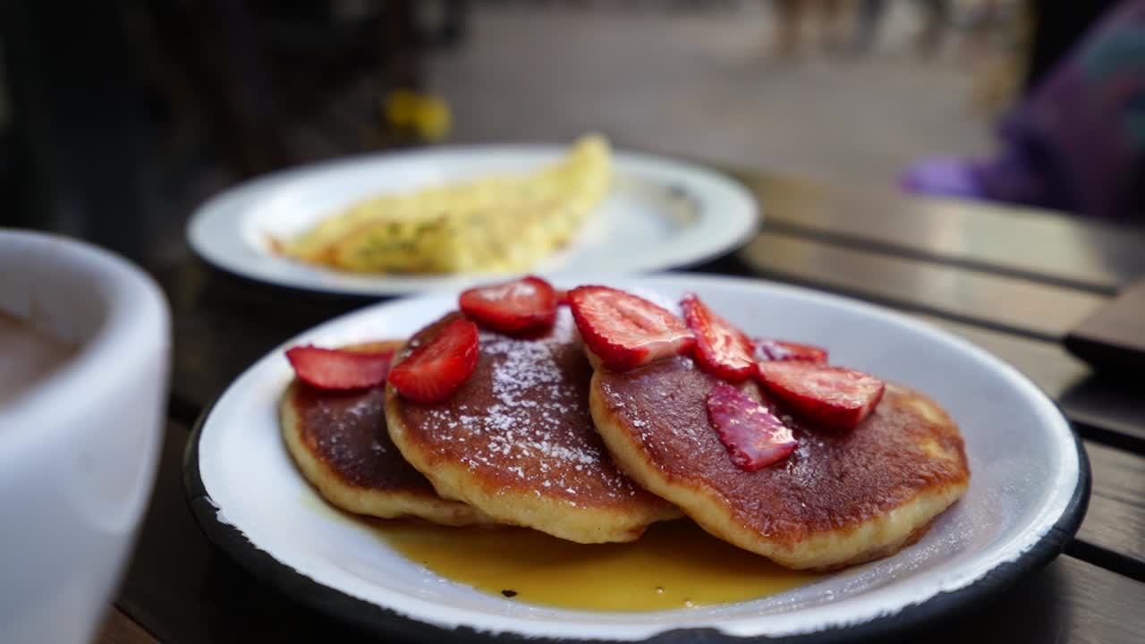 Outdoor breakfast, plate with three pancakes, strawberries and organic honey