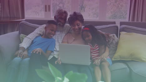 Spots-of-light-against-african-american-grandparents-and-grandchildren-using-laptop-at-home