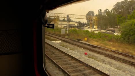 steady side point of view shot of an indian train compartment window, while the train is moving and arriving at the station