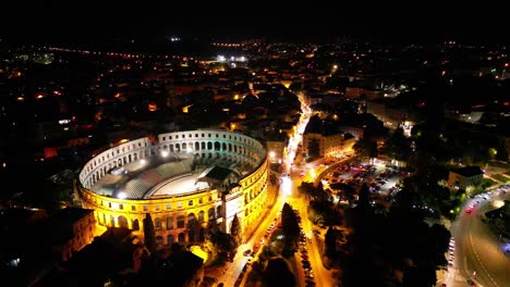 ancient roman amphitheater lit up at night amid pula's city lights. pula, croatia
