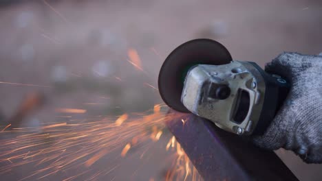 close up of worker man hand cutting metal with grinder. sparks while grinding iron