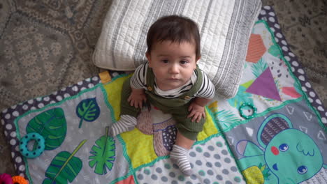 wide shot of hispanic baby in living room with pillow and play mat