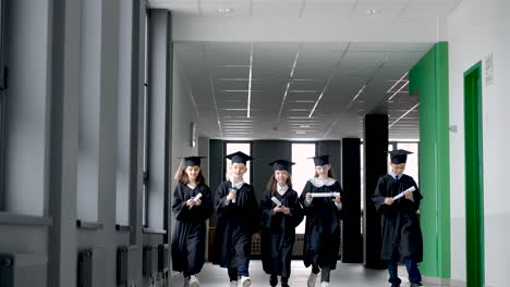 Group-Of-Happy--Preschool-Students-In-Mortarboard-And-Gown-Greeting-Their-Teacher-1