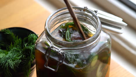 pressing pickles down in a jar filled with brine