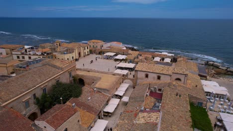 scenic drone flyover of marzamemi in sicily, italy. fishing boats, tiled roofs, and seaside charm.