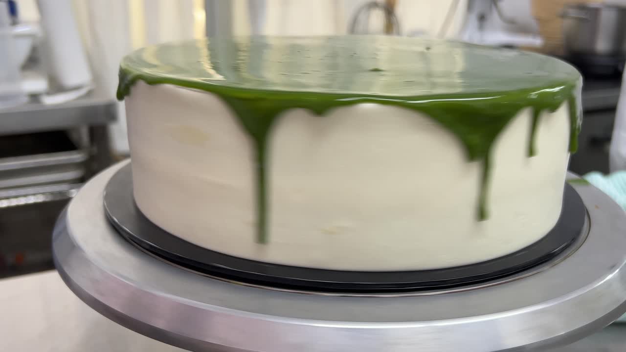 맛있는 쉬폰 케이크에 말차 초콜릿 미러 글레이즈를 매끄럽게 하기 위해 턴테이블을 돌리고 돌리고, 맛있는 디저트를 준비하는 패스트리 메이커의 클로즈업 샷