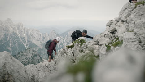 un grupo de excursionistas escalando la montaña sobre rocas con equipo de escalada completo