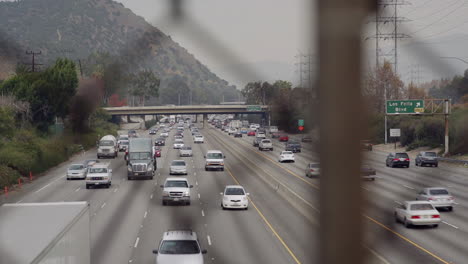 Looking through an overpass fence towards a busy highway on an overcast day.