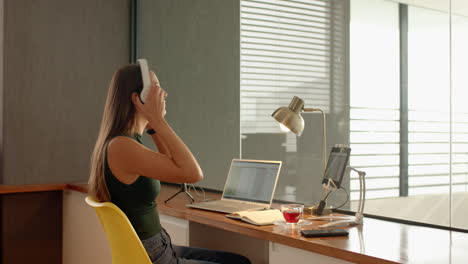talking on smartphone, woman working on laptop at home office desk