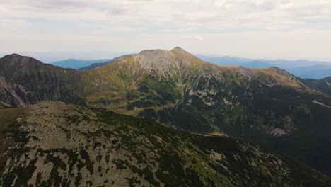 aerial view showing tall layered mountain ranges and peaks on a clouded grim day