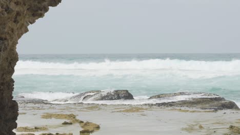 wide shot of wave hitting a rock