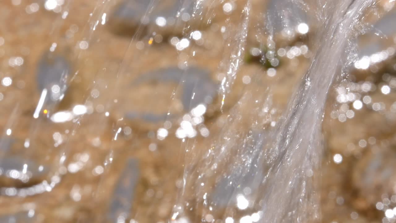 Primo piano di acqua cristallina che scorre su uno sfondo rustico in pietra. Un dettaglio rinfrescante e spirituale nello storico Convento del Carmen ad Alhama.