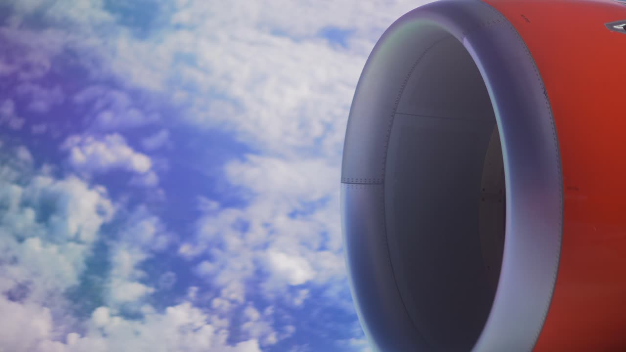 Flymotor, udsigt fra et flyvindue under flyvning over en blå himmel fyldt med lette skyer, fredelig ferierejse