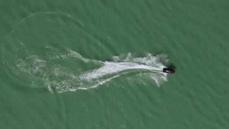 Jinete-En-Sea-Doo-Jet-Ski-Acelerando-En-La-Superficie-Del-Agua-Del-Lago,-Sobrecarga-Aérea