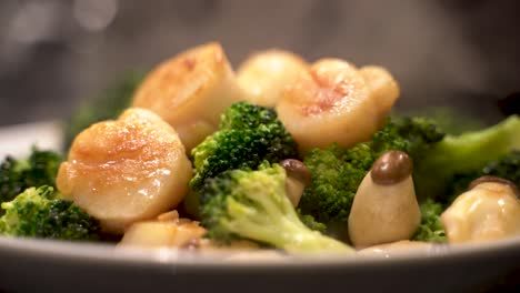 close-up shot of delicious hot freshly cooked scallop, broccoli and mushroom steaming on plate