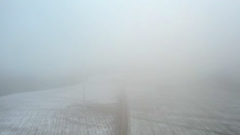 foggy scene of windmill farm on a mountain side covered in clouds - aerial view