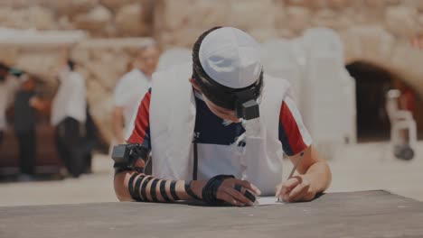 young bar mitzvah boy writes letter of prayer in jerusalem israel at the western wailing wall