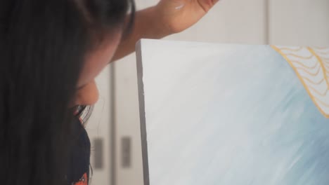 mujer artista pinta cuidadosamente los lados del lienzo de una obra de arte abstracta al óleo