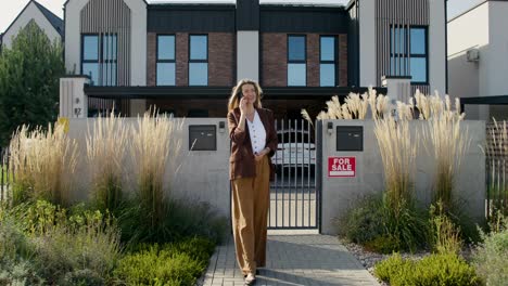 woman talking on phone in front of house for sale